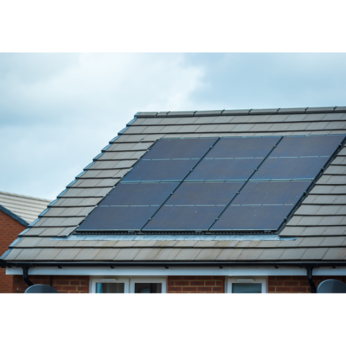 Solar panels installed on the sloped roof of a house with grey tiles, under a partly cloudy sky. Only the upper part of the building is visible, highlighting modern energy solutions like boilers on Finance.